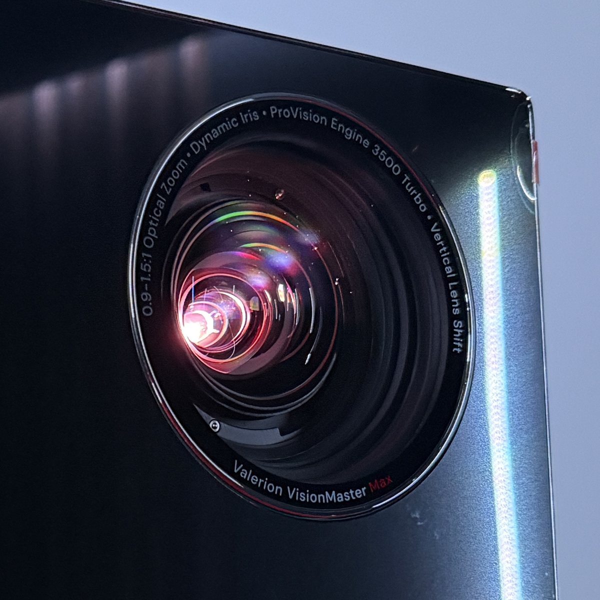 Nahaufnahme des Objektivs mit leuchtender Linse. Auf dem Ring steht: 0.9–1.5:1 Optical Zoom, Dynamic Iris, ProVision Engine 3500 Turbo, Vertical Lens Shift, darunter Valerion VisionMaster Max.
